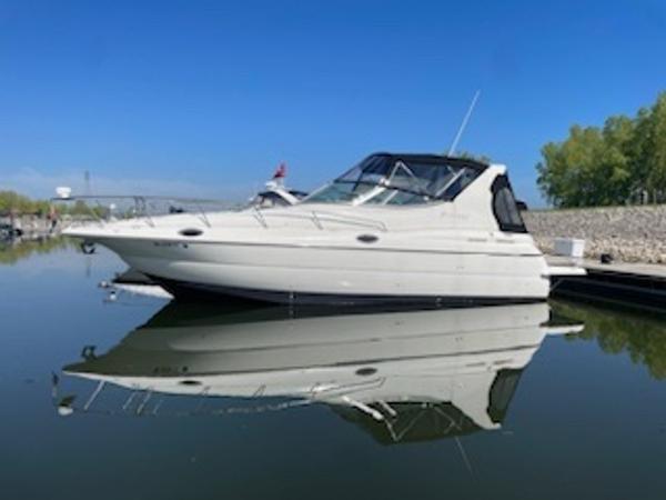 The Image of 1998 Cruisers Yachts 3075 Express boat docked on calm water. - 1