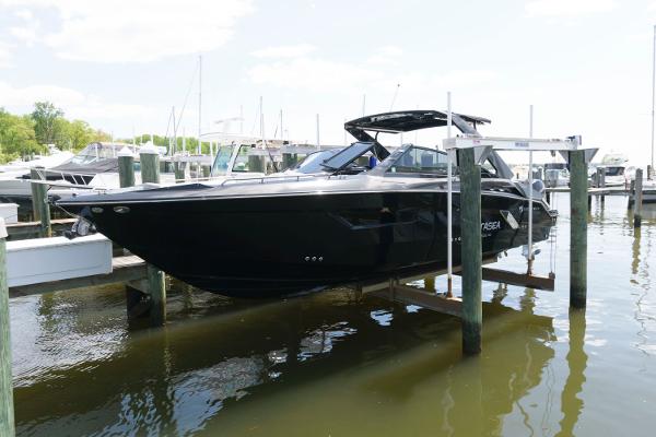 Slide: The Image of 2020 Cruisers Yachts 338 SS OB in marina, black hull, docked on lift. - 1
