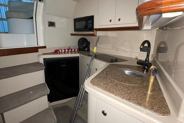 Slide: The Image of 2001 Cruisers Yachts 3470 Express interior kitchen with sink, microwave, and stairs. - 8