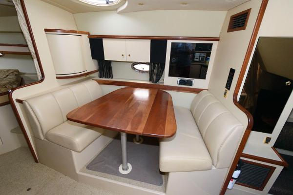Slide: The Image of 2002 Cruisers Yachts 3470 Express interior dining area with wooden table and beige seating. - 13