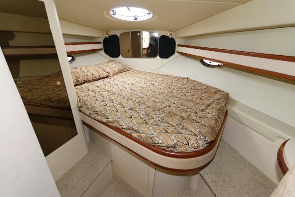 Slide: The Image of 2002 Cruisers Yachts 3470 Express cabin with a cozy bed and porthole windows. - 16