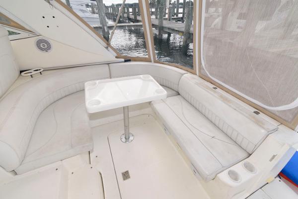 Slide: The Image of 2002 Cruisers Yachts 3470 Express cockpit with white seating and table, dockside view. - 7