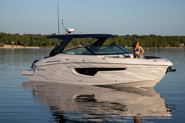 Slide: The Image of 2023 Cruisers Yachts 34 GLS on calm water with a person standing on deck. - 11