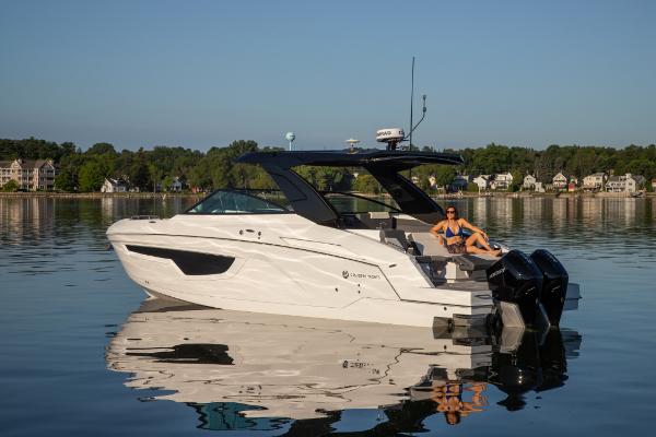 Slide: The Image of 2023 Cruisers Yachts 34 GLS on a serene lake with a person relaxing. - 14