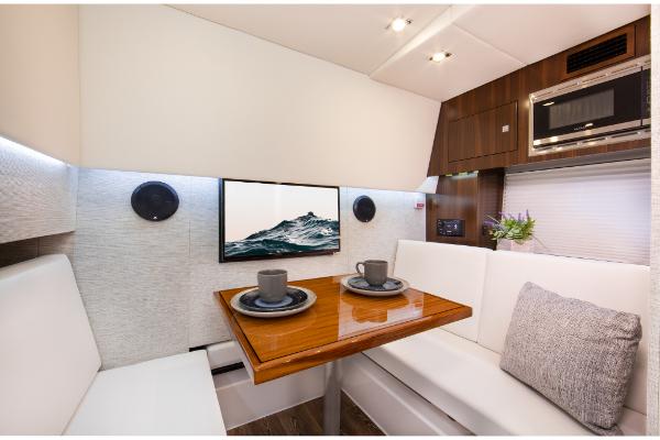 Slide: The Image of 2023 Cruisers Yachts 34 GLS interior dining area with TV, microwave, and seating. - 34