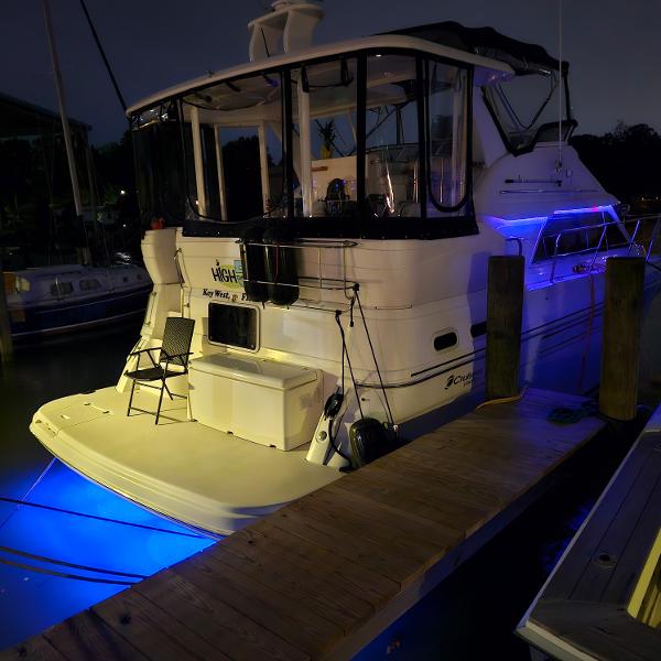 Slide: The Image of 1999 Cruisers Yachts 3750 Motoryacht docked at night with blue underwater lights. - 13