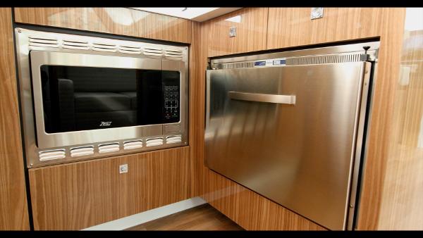 Slide: The Image of Modern kitchen appliances in 2024 Cruisers Yachts 50 Cantius, featuring a microwave and stainless steel fridge. - 29