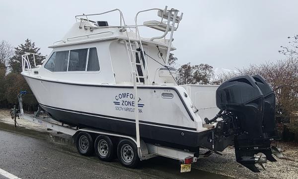 Slide: The Image of 2012 Crusader Boats outboard cruiser on trailer, parked on a wet road. - 2