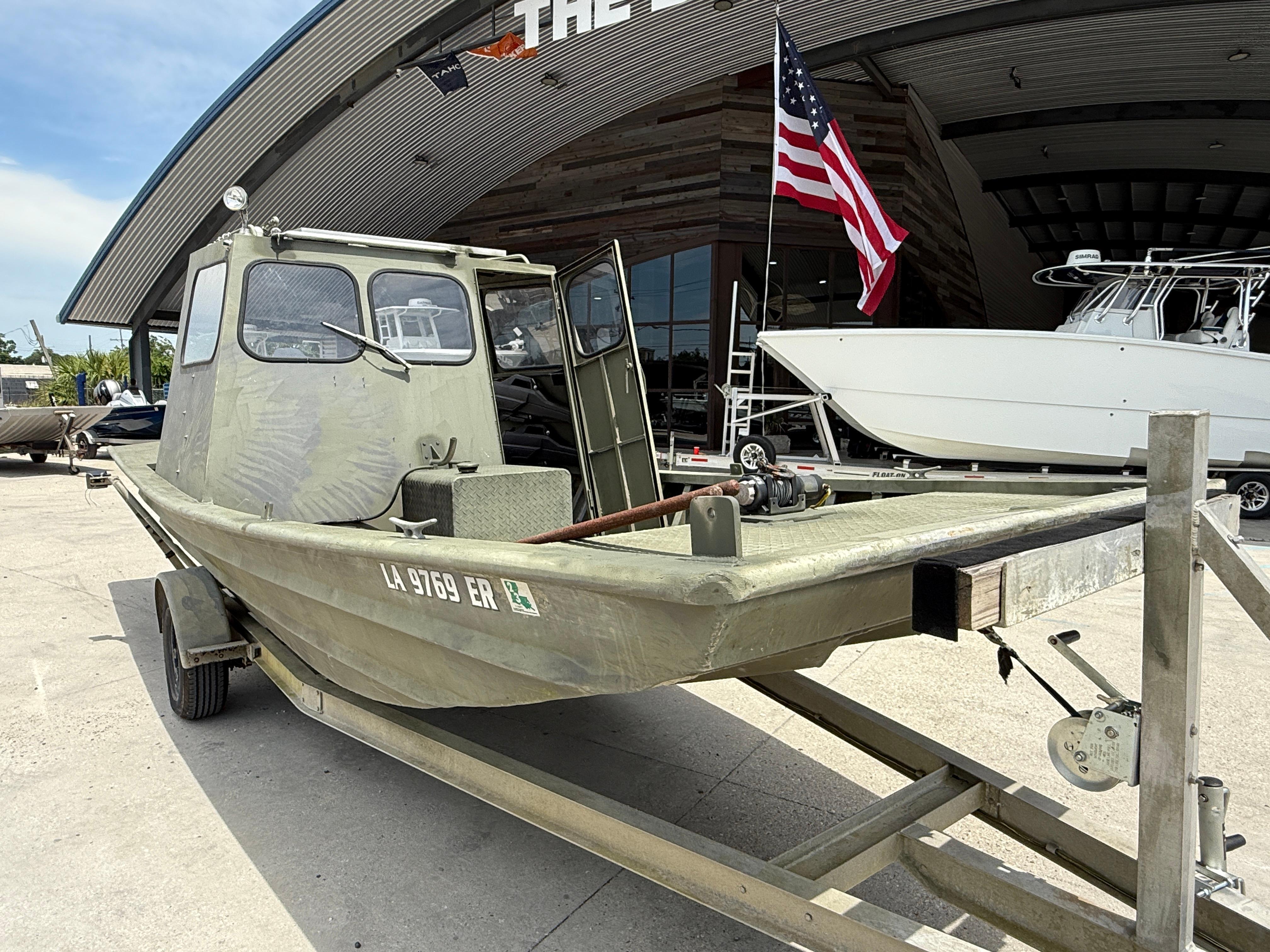 Slide: The Image of Custom 1995 Aluminum 2073 Cabin boat on trailer, parked outside a building with American flag. - 1