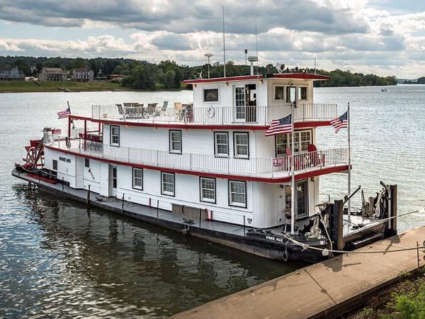 Slide: The Image of 1936 Custom Dravo Sternwheeler docked by a river with American flags. - 0
