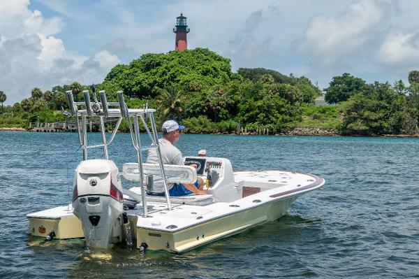 Slide: The Image of Man driving 2017 Custom Envi Redfisher boat near a lighthouse on a sunny day. - 1