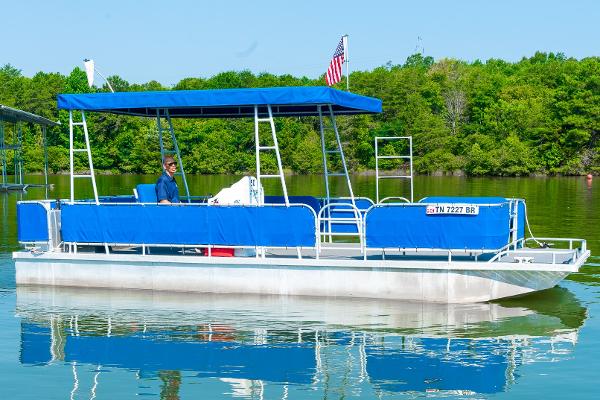 Slide: The Image of Custom 2000 Lake Wind 25 x 10 Pontoon boat on a calm lake with blue canopy. - 0