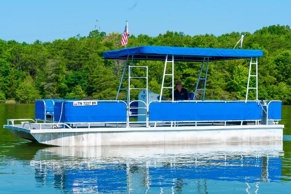 Slide: The Image of Custom 2000 Lake Wind 25 x 10 Pontoon boat with blue canopy on a lake. - 1
