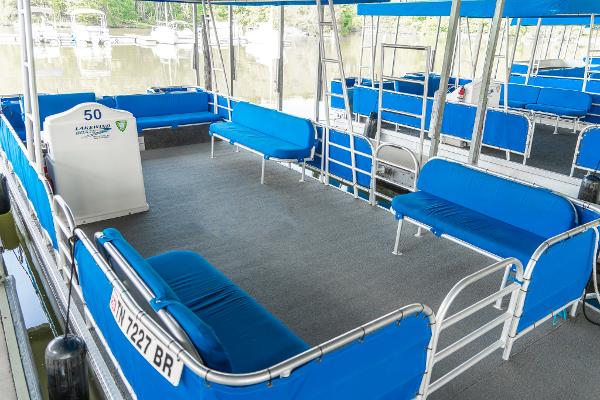 Slide: The Image of Custom 2000 Lake Wind 25 x 10 Pontoon with blue seating and canopy on calm water. - 8