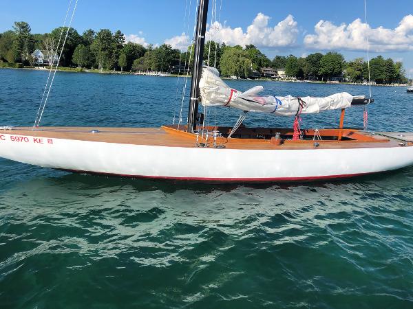 Slide: The Image of 1934 Custom Northern Michigan NM sailboat on a serene lake with lush green shoreline. - 0