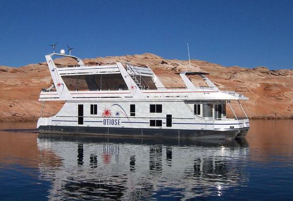 Slide: The Image of Custom 2005 houseboat The Entourage Shares #21,33 and 40 on calm water near rocky shore. - 2