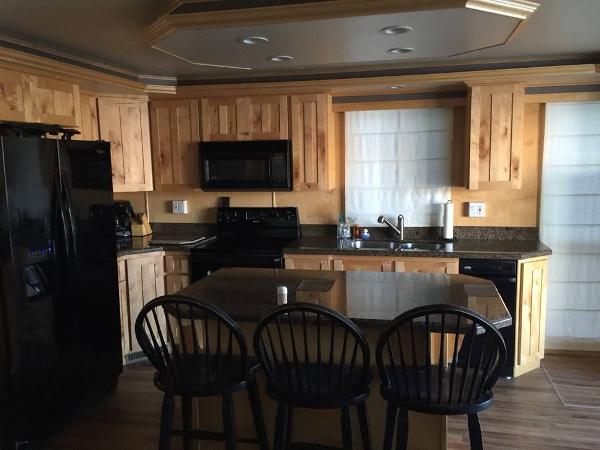 Slide: The Image of Modern kitchen with wooden cabinets, black appliances, and a central island with bar stools. - 23