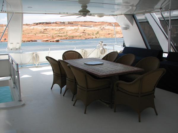 Slide: The Image of Luxury yacht deck with dining table, wicker chairs, and scenic water view. Custom model: The Entourage Shares #21,33 and 40, - 9