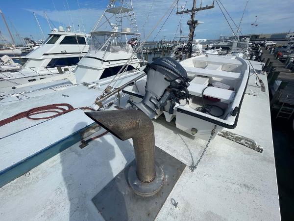 Slide: The Image of 1987 Custom Trawler Biloxi Lugger docked, featuring an outboard motor and deck equipment. - 15