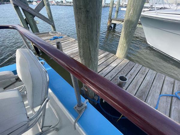 Slide: The Image of 1987 Custom Trawler Biloxi Lugger docked, featuring wooden railing and seating, with marina view. - 17