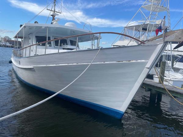 Slide: The Image of 1987 Custom Trawler Biloxi Lugger docked in marina, white hull, blue trim, clear sky. - 2