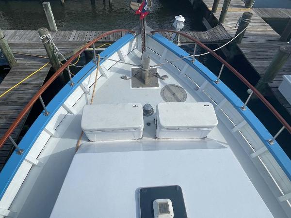 Slide: The Image of 1987 Custom Trawler Biloxi Lugger docked, featuring a spacious deck with storage compartments. - 4