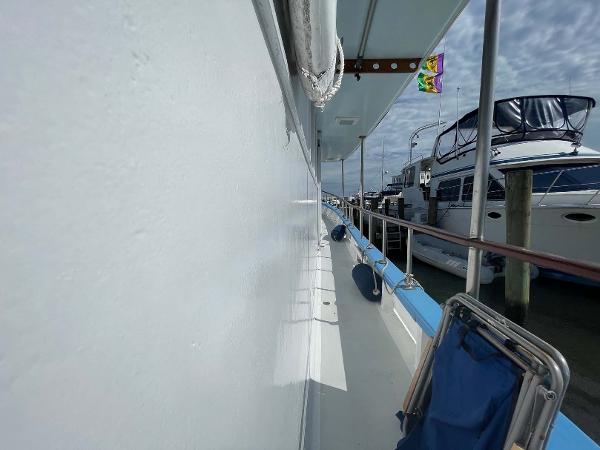 Slide: The Image of Side view of 1987 Custom Trawler Biloxi Lugger docked, featuring deck and nearby boats. - 8