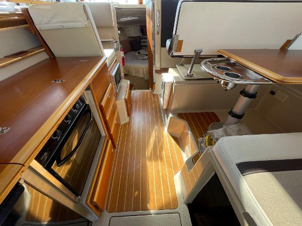 Slide: The Image of Interior of 2016 Cutwater 30 Sedan LE, featuring wood flooring and compact kitchen area. - 25