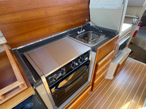 Slide: The Image of 2016 Cutwater 30 Sedan LE kitchen with stove, sink, and wood cabinetry. - 31