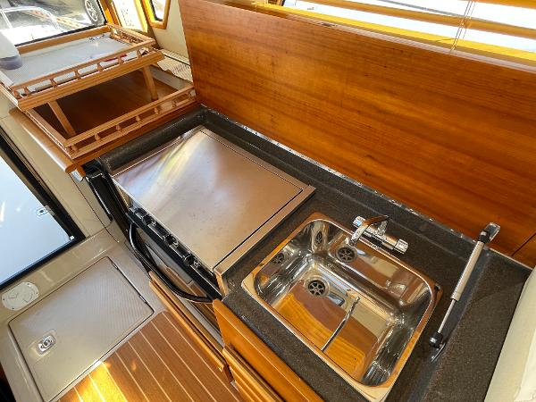 Slide: The Image of 2016 Cutwater 30 Sedan LE kitchen with stove, sink, and wooden cabinetry. - 32