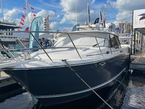 Slide: The Image of 2023 Cutwater C-288 boat docked at a marina with flags and buildings in the background. - 6