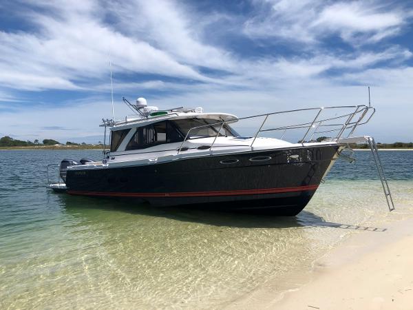 Slide: The Image of 2025 Cutwater C-32 Sedan boat on sandy shore under blue sky. - 1