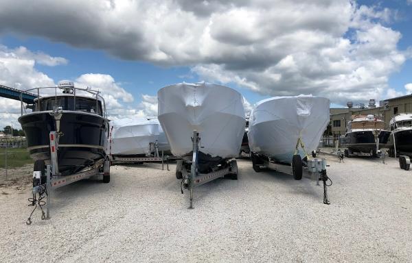 Slide: The Image of 2025 Cutwater C-32 Sedan boats on trailers under cloudy sky. - 24