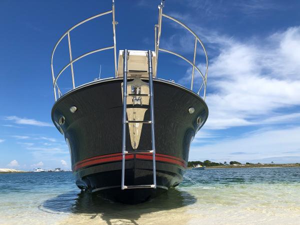 Slide: The Image of 2025 Cutwater C-32 Sedan boat on sandy shore under blue sky. - 3
