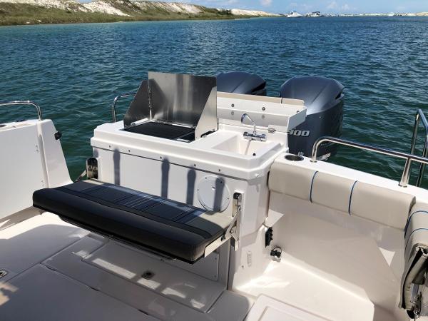Slide: The Image of 2025 Cutwater C-32 Sedan boat with outdoor seating and dual engines on a serene lake. - 6
