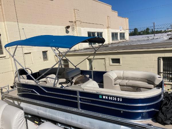 Slide: The Image of 2021 Cypress Cay C232 Tritoon with blue canopy, docked near a beige building. - 11