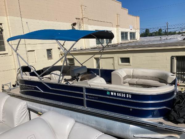 Slide: The Image of 2021 Cypress Cay C232 Tritoon with blue canopy, docked near a beige building. - 4