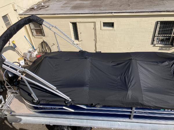 Slide: The Image of 2021 Cypress Cay C232 Tritoon with black cover, parked near a building. - 6