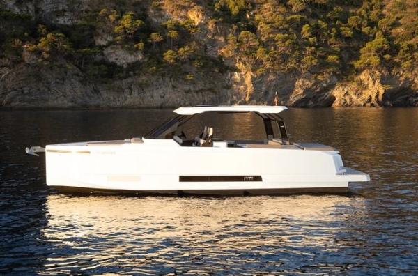 Slide: The Image of 2024 De Antonio Yachts D36 OPEN on serene water with rocky backdrop. - 0