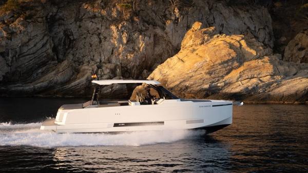 Slide: The Image of 2024 De Antonio Yachts D36 OPEN cruising near rocky coastline at sunset. - 1