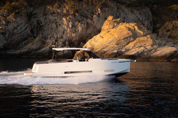 Slide: The Image of 2025 De Antonio Yachts D36 OPEN cruising near rocky coastline at sunset. - 1