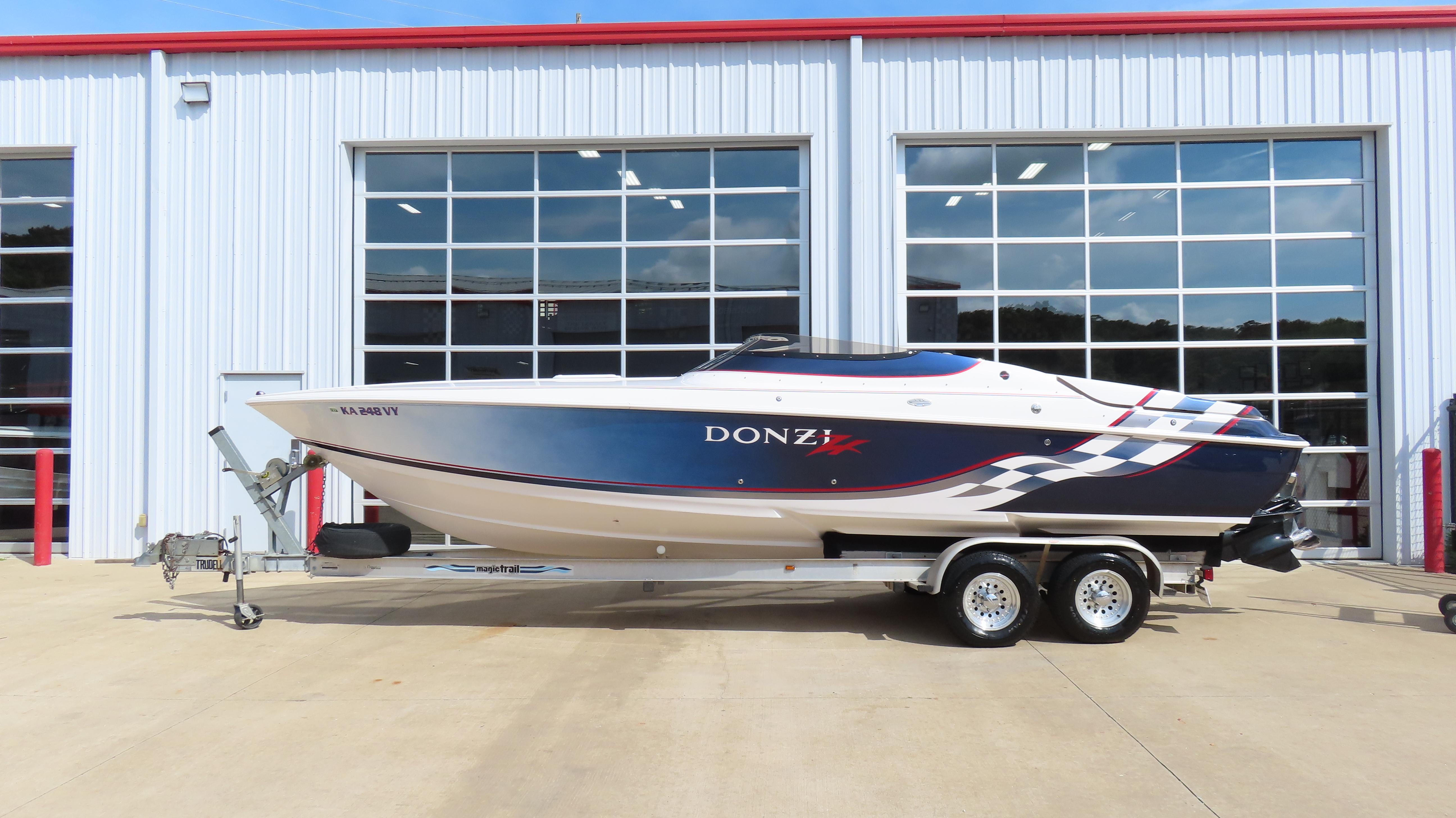 Slide: The Image of 2000 Donzi 28ZX speedboat on trailer, parked outside a garage with glass doors. - 0
