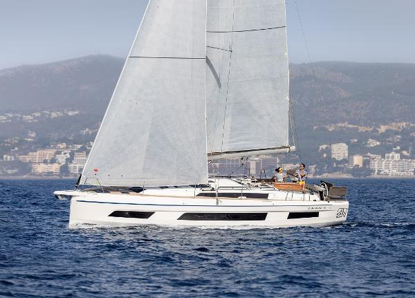 Slide: The Image of 2024 Dufour 41 sailboat cruising on open water with coastal city in background. - 0