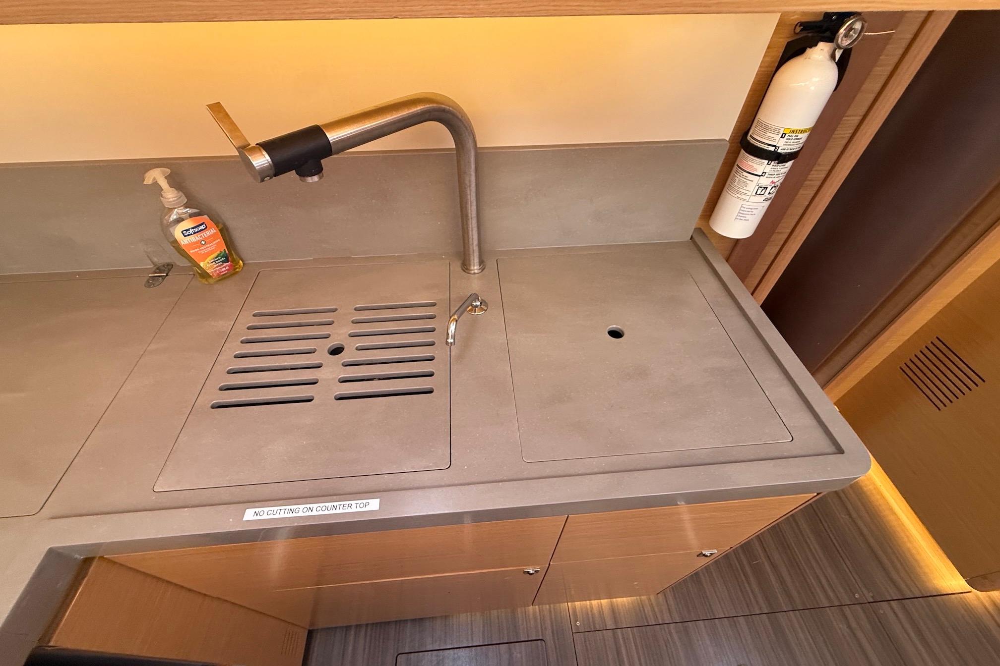Slide: The Image of Modern kitchen sink area on 2022 Dufour 530 yacht with faucet and fire extinguisher. - 16