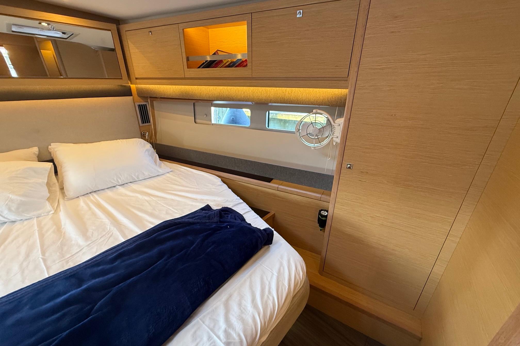 Slide: The Image of 2022 Dufour 530 yacht cabin with cozy bed, wooden interior, and storage compartments. - 21