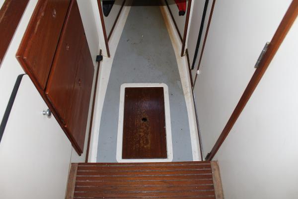 Slide: The Image of 1989 Dyer Downeast boat interior hallway with wooden cabinets and floor hatch. - 11