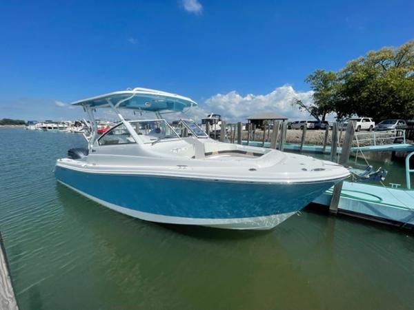 Slide: The Image of 2024 Edgewater 280 CX boat docked in a marina on a sunny day. - 0