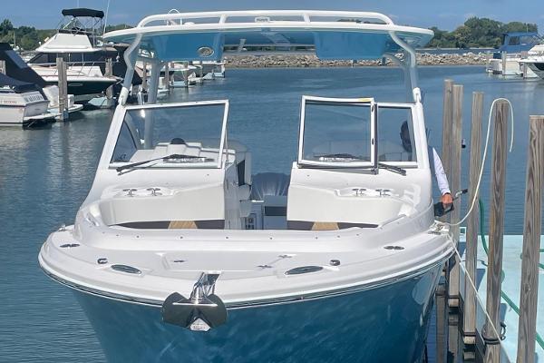 Slide: The Image of 2024 Edgewater 280 CX boat docked at a marina with open windshields. - 2