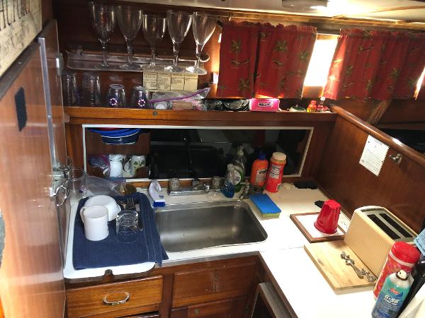 Slide: The Image of 1963 Egg Harbor Convertible Cruiser kitchen with sink, glassware, and red floral curtains. - 19