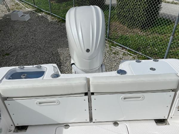 Slide: The Image of 2023 Everglades 235CC boat with white seating and engine, parked near a chain-link fence. - 28